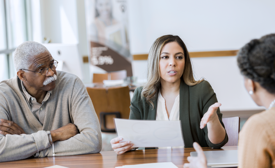 Advocacy report, photo of 3 black and brown people, with one being a woman in business clothes speaking decisively to them.